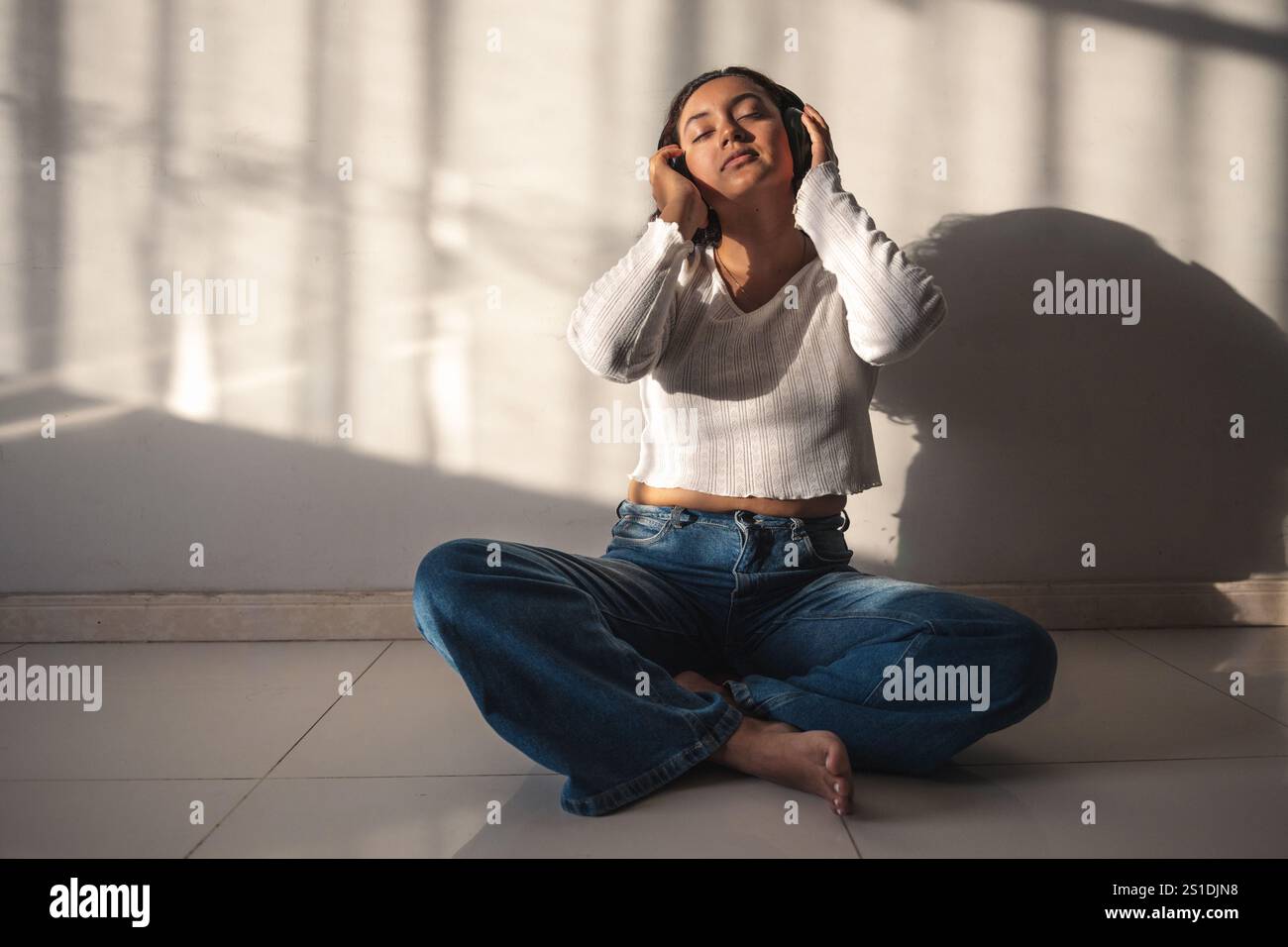 Donna che ascolta musica con le cuffie a casa Foto Stock