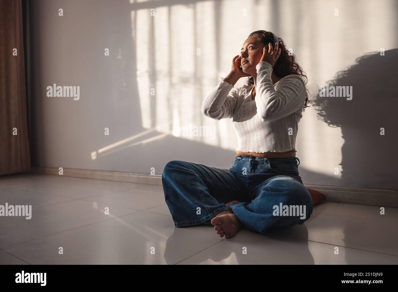 Donna che ascolta musica con le cuffie a casa Foto Stock