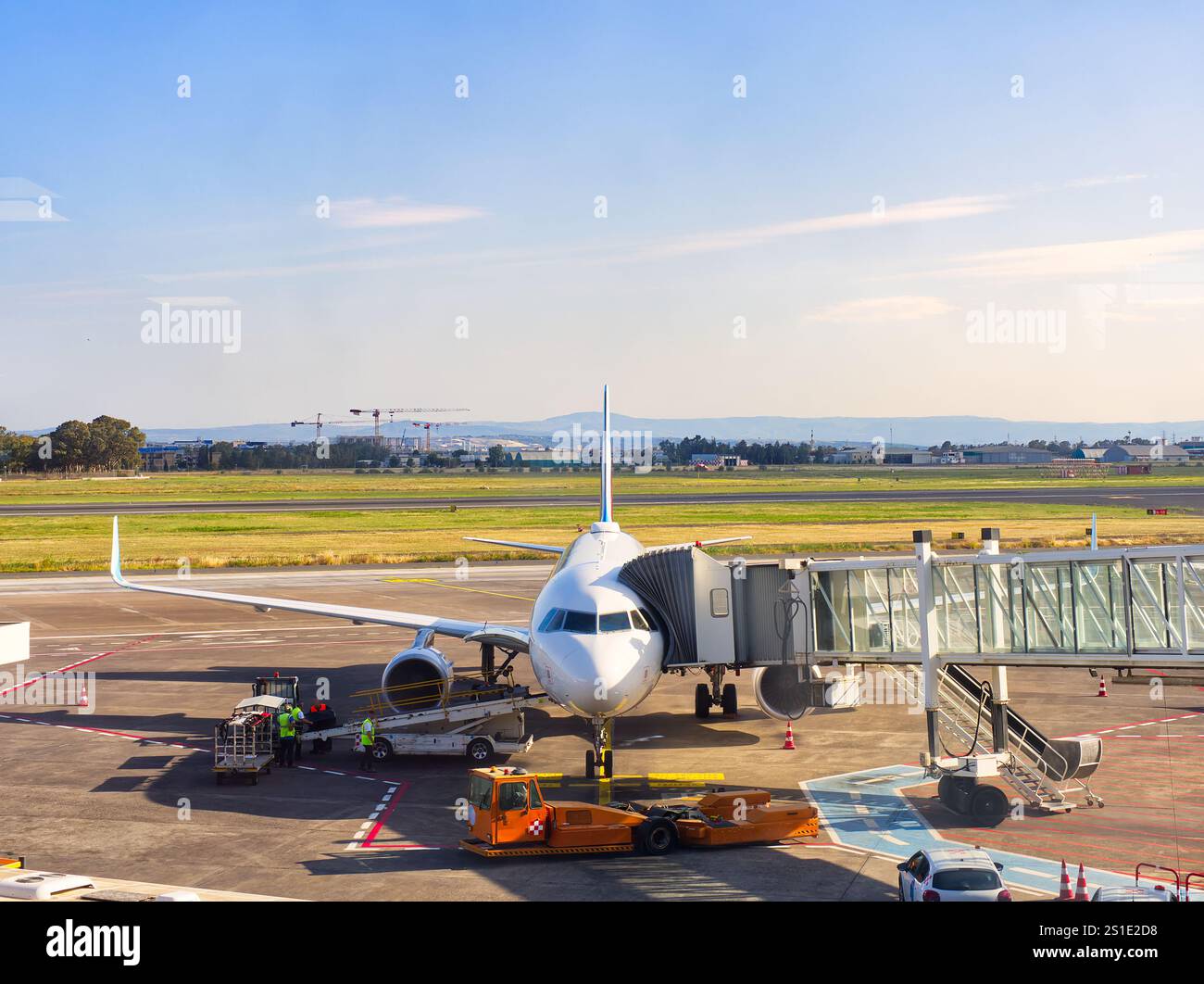 Velivolo commerciale parcheggiato presso il JET Bridge con equipaggio di terra e attrezzature su asfalto Foto Stock