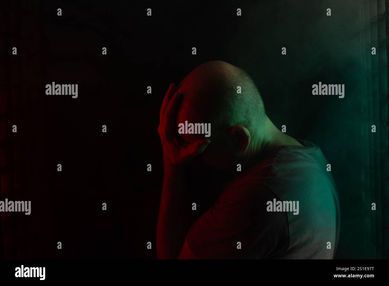 Uomo bianco, calvo e barbuto, testa giù. Ritratto in studio con sfondo nero e luci colorate. Persona sudamericana. Foto Stock