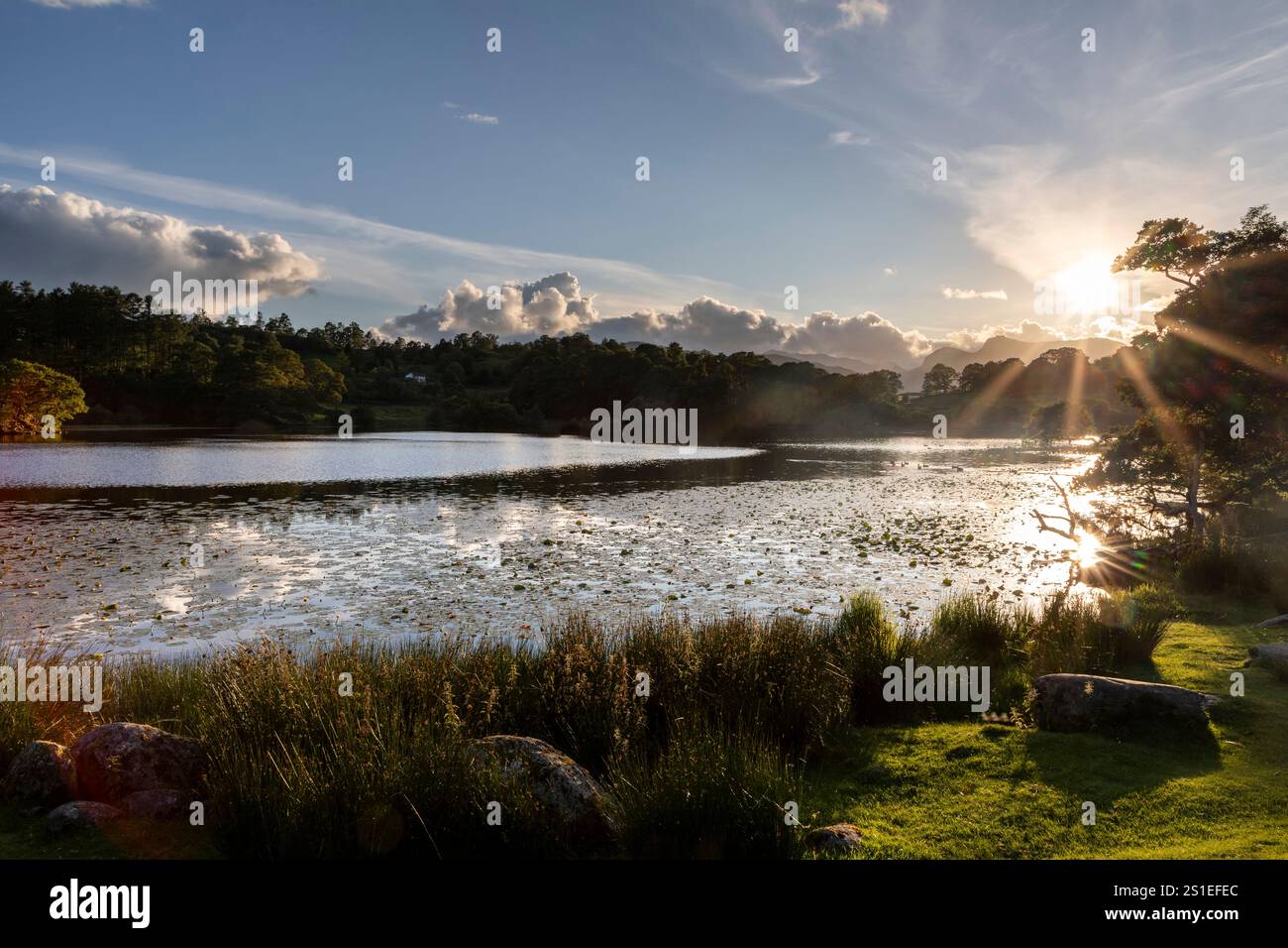 loughrigg tarn vicino al quartiere dei laghi con il ponte di skelwith al tramonto con le pike di langdale sullo sfondo e il bagliore delle lenti dal sole nessuno Foto Stock