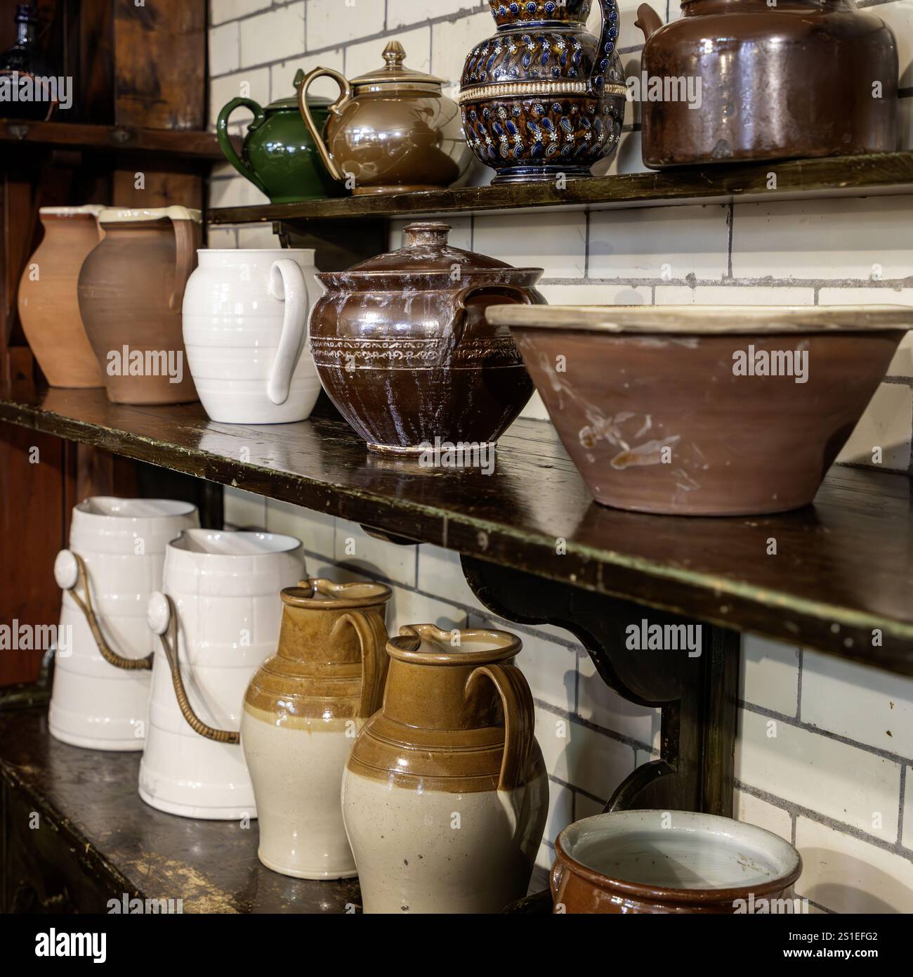 collezione di caraffe e ciotole da cucina vittoriane sugli scaffali con pareti piastrellate bianche Foto Stock