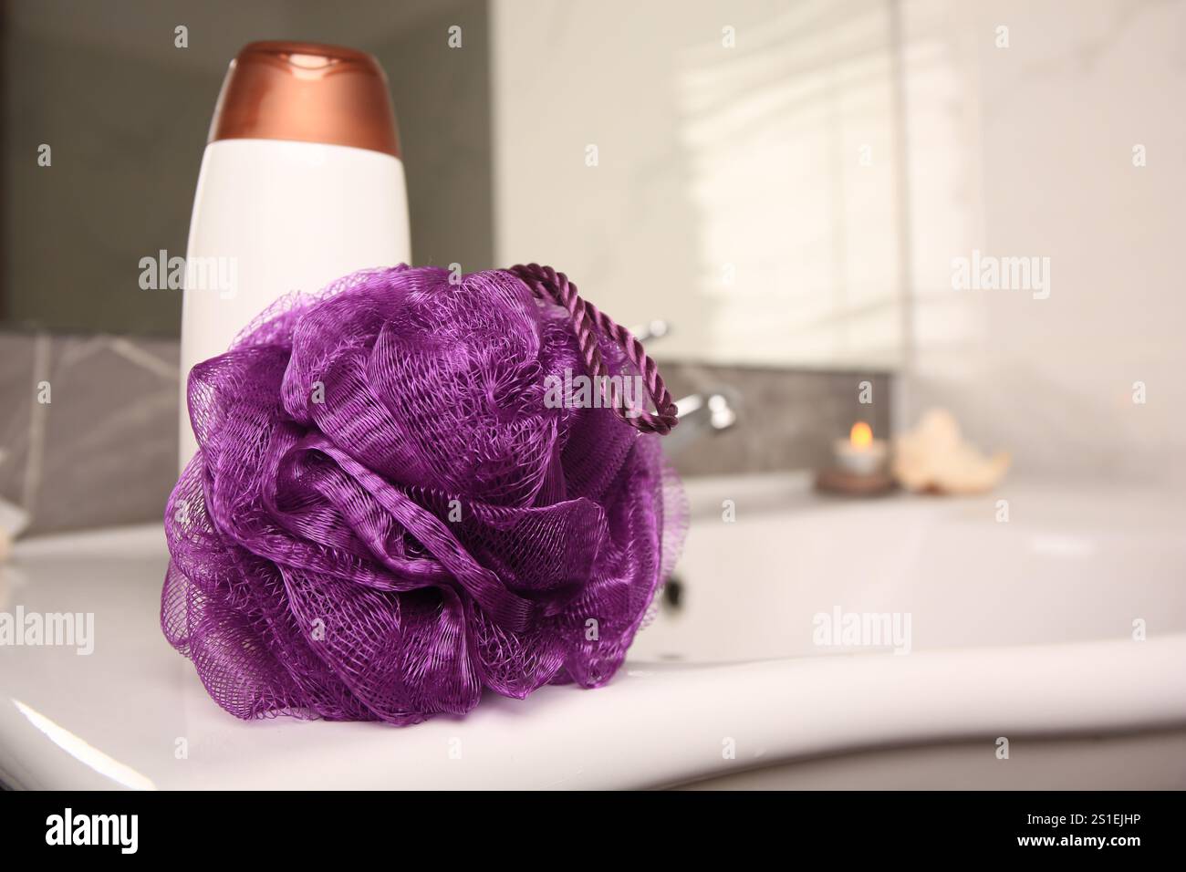 Soffio doccia viola e bottiglia di gel per il lavaggio del corpo sul lavandino in bagno, spazio per il testo Foto Stock