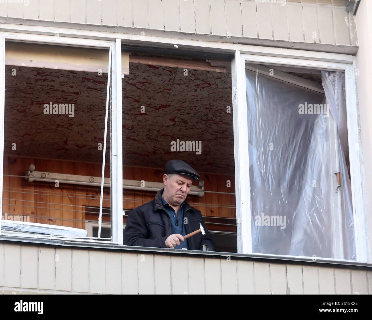 KIEV, UCRAINA - 1 GENNAIO 2025 - Un uomo ripara una finestra rotta in un edificio residenziale nel distretto di Sviatoshynskyi danneggiato da uno sciopero russo di droni, Kiev, capitale dell'Ucraina. Foto Stock