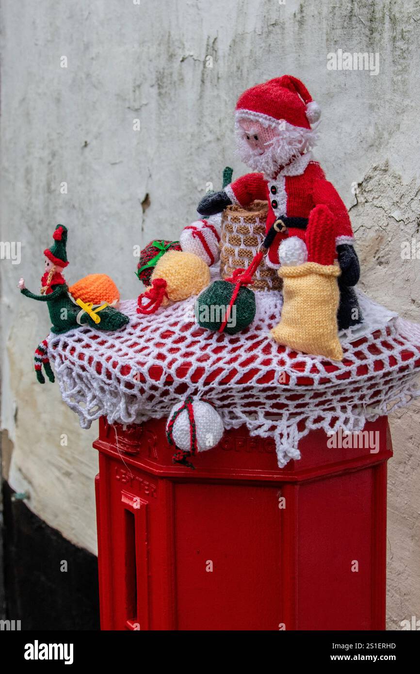 Su un angolo di Framlingham, una scatola a colonna rossa vittoriana "Ludlow" è stata decorata per Natale con una scena di Babbo Natale a maglia posta in cima. Foto Stock