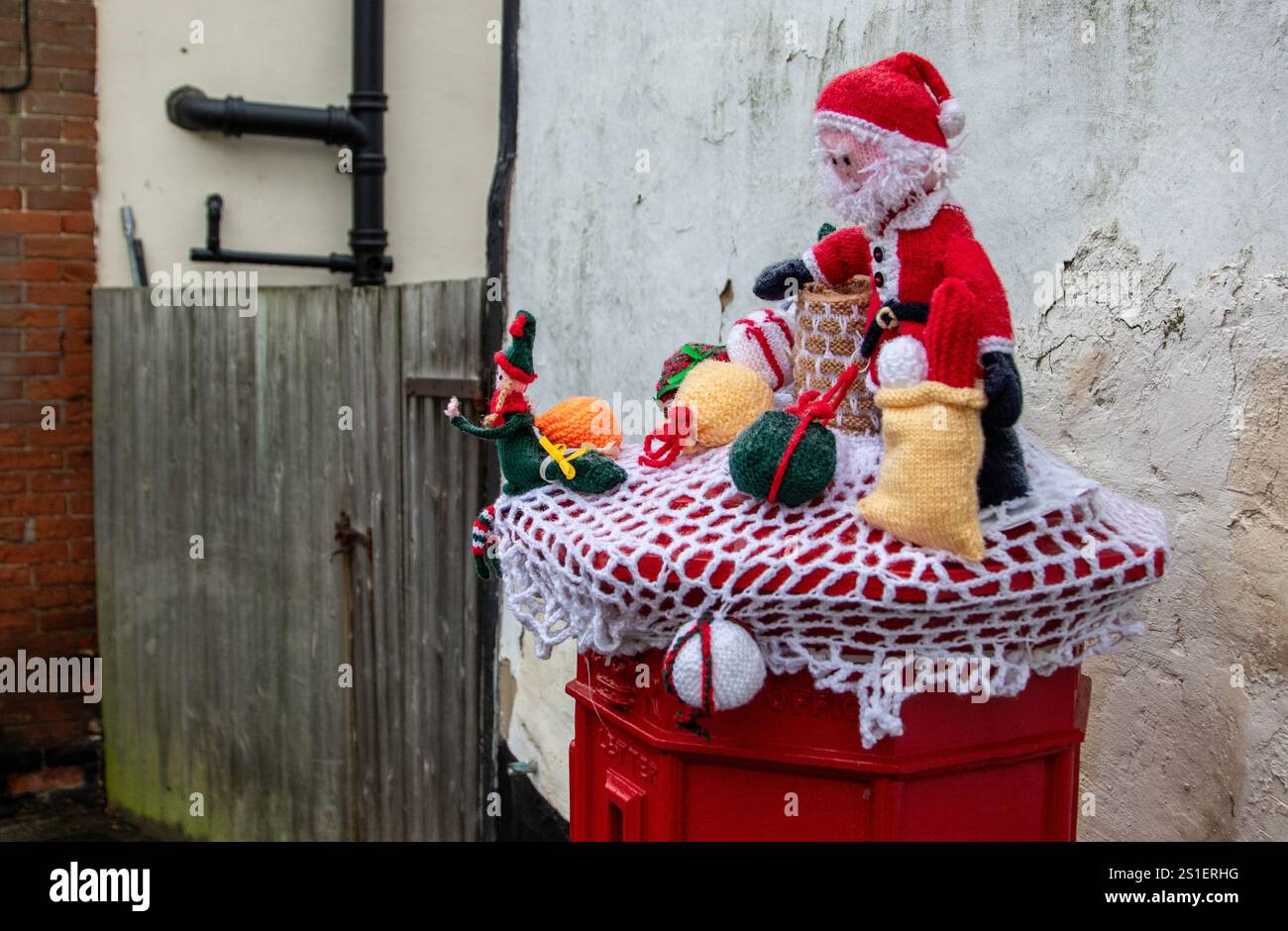 Su un angolo di Framlingham, una scatola a colonna rossa vittoriana "Ludlow" è stata decorata per Natale con una scena di Babbo Natale a maglia posta in cima. Foto Stock