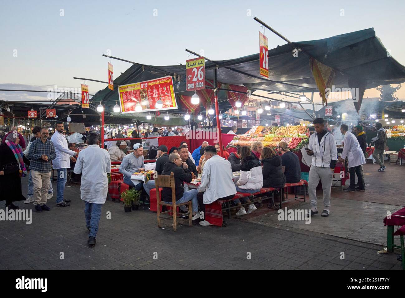 persone sedute in bancarelle di cibo affollate in prima serata piazza jemaa el-fna marrakech, marocco Foto Stock
