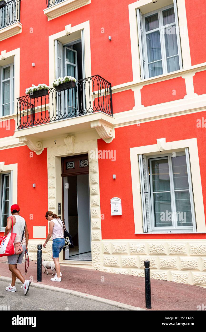 Cannes Francia, Provence Alpes Cote d'Azur, Rue de Port, storico edificio rosso le Dom Apartments, esterno, uomo donna coppia residenti pedoni Foto Stock