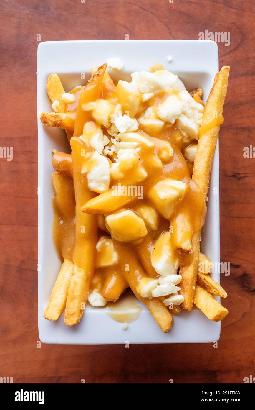 Piatto di poutine con patatine croccanti condite con cagliate di formaggio e ricco sugo di carne bruno in un ristorante locale di Alberta, Canada Foto Stock