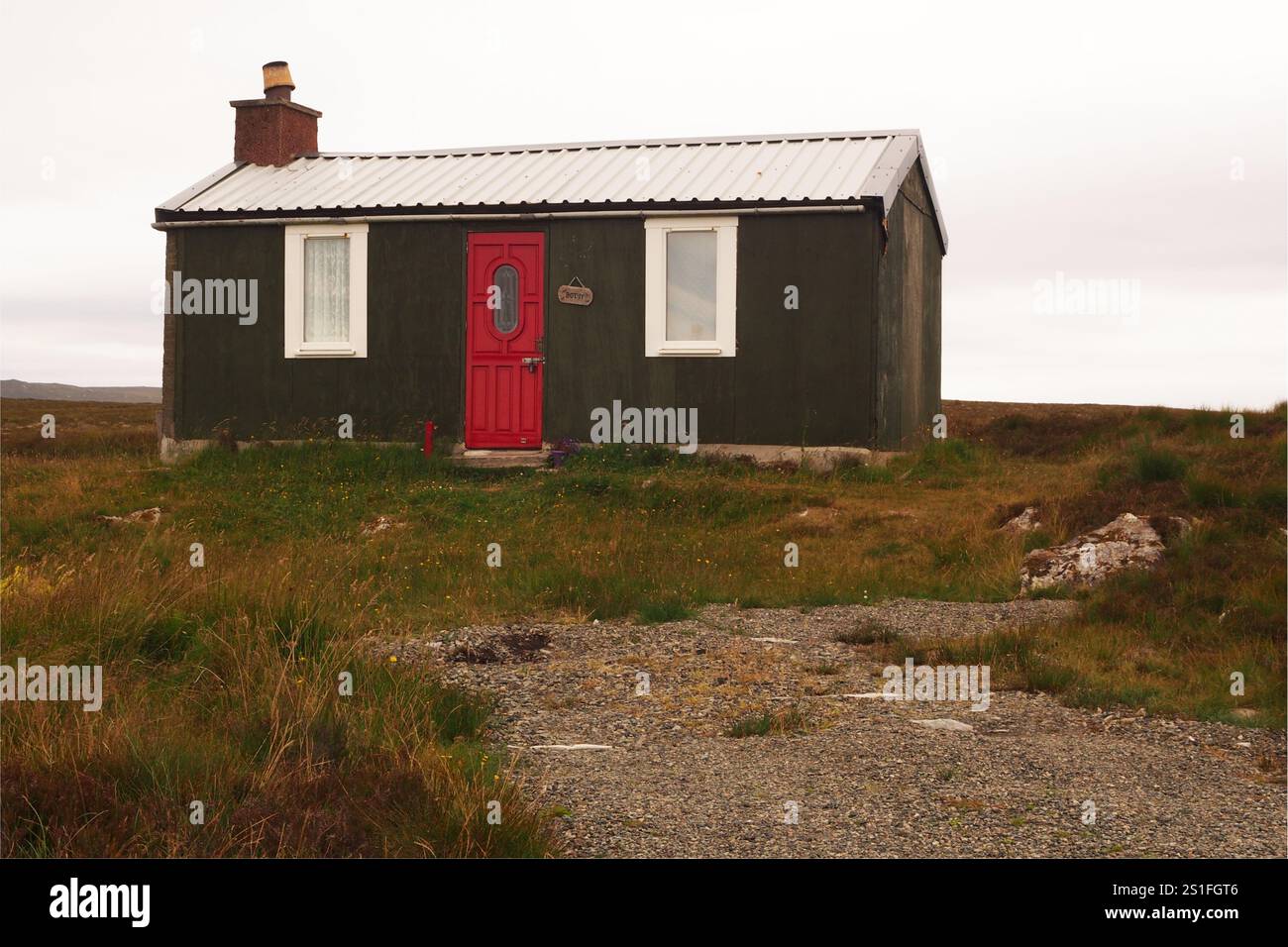 Un bothy scozzese in un paesaggio remoto sull'isola di Lewis, che mostra l'edificio di base nel paesaggio selvaggio con una porta rossa e un tetto in metallo Foto Stock