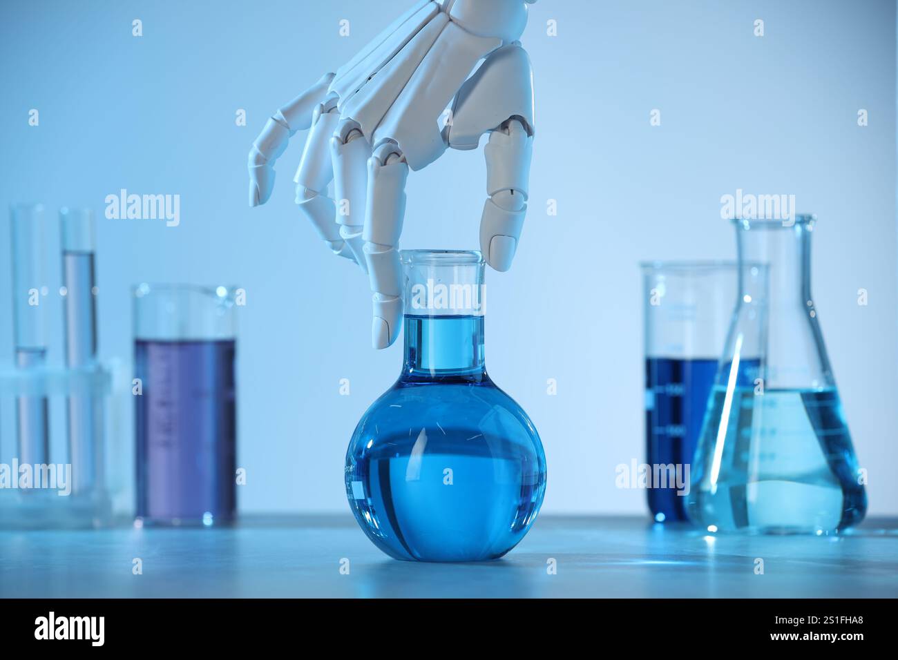 Intelligenza artificiale. Mano robot con fiasca al tavolo con luce blu, primo piano Foto Stock