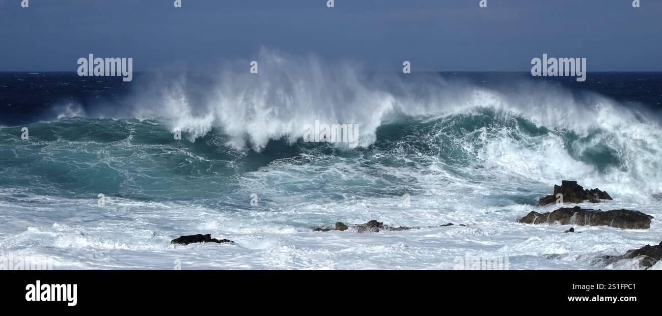 Grandi onde turchesi si schiantano di fronte alle scogliere. Formato Panorama orizzontale. Di fronte alla scogliera si capovolge una grande onda turchese Foto Stock