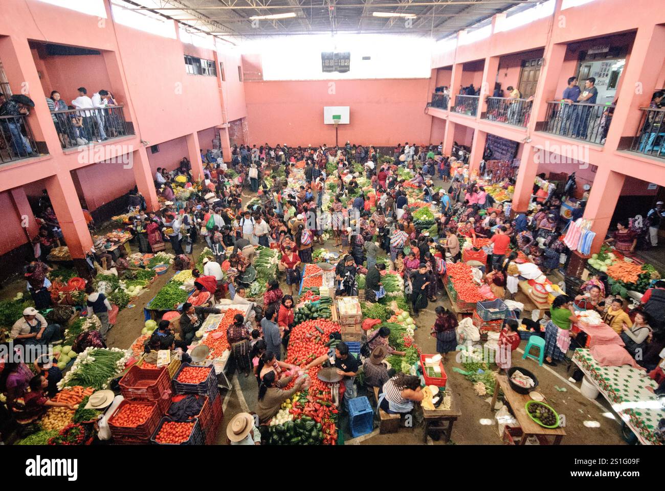 Mercato di prodotti e tessuti di Chichicastenango Chichicastenango Guatemala | CHICHICASTENANGO, Guatemala — Frutta e verdura fresche sono esposte in vendita nella palestra di Chichicastenango come parte del famoso mercato domenicale, uno dei più grandi e colorati mercati indigeni del Guatemala. Chichicastenango (conosciuto anche come "Chichi") è una città indigena K'iche' Maya nell'altopiano del Guatemala, a circa 90 miglia (145 km) a nord-ovest della Città del Guatemala ad un'altitudine di quasi 6.500 piedi (1.980 metri). La città ospita i suoi rinomati mercati due volte alla settimana il giovedì e la domenica, attirando sia la gente del posto che i tou Foto Stock