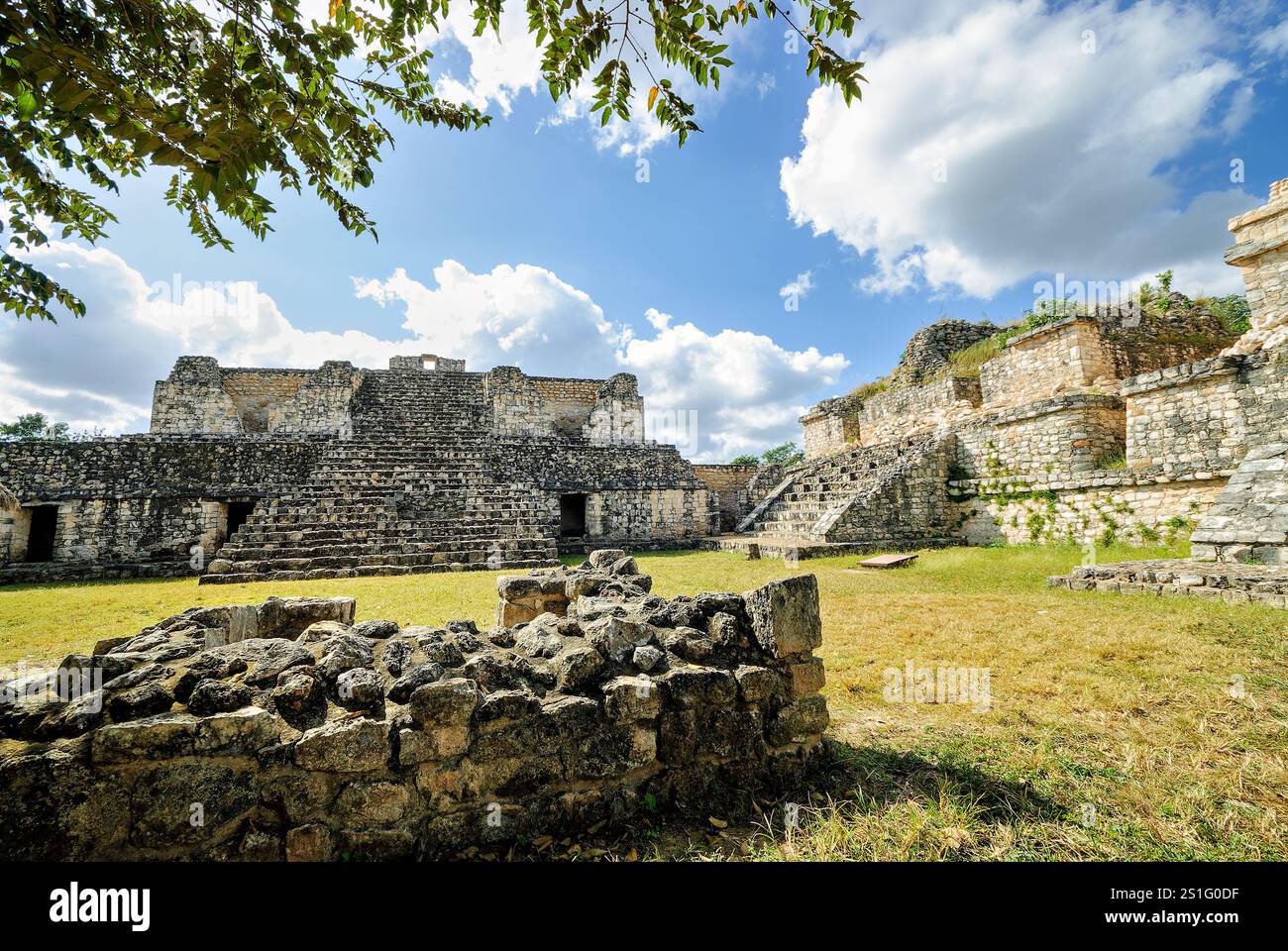 EK Balam Ancient Maya Structures Yucatan Mexico // EK BALAM, Mexico - Una grande area cortile circondata da antiche strutture Maya nel sito archeologico di Ek Balam (noto anche come Ek' Balam) nella penisola dello Yucatan in Messico. Il sito, il cui nome si traduce in "giaguaro nero" in lingua maya, fiorì dal Medio Preclassico fino al periodo Classico terminale, raggiungendo il suo apice tra il 770-840 d.C. sotto il re Ukit Kan le'k Tok. EK Balam è stata la capitale dell'antico regno di Talol e si distingue per la sua eccezionale conservazione di opere d'arte in stucco e l'elaborato l Foto Stock