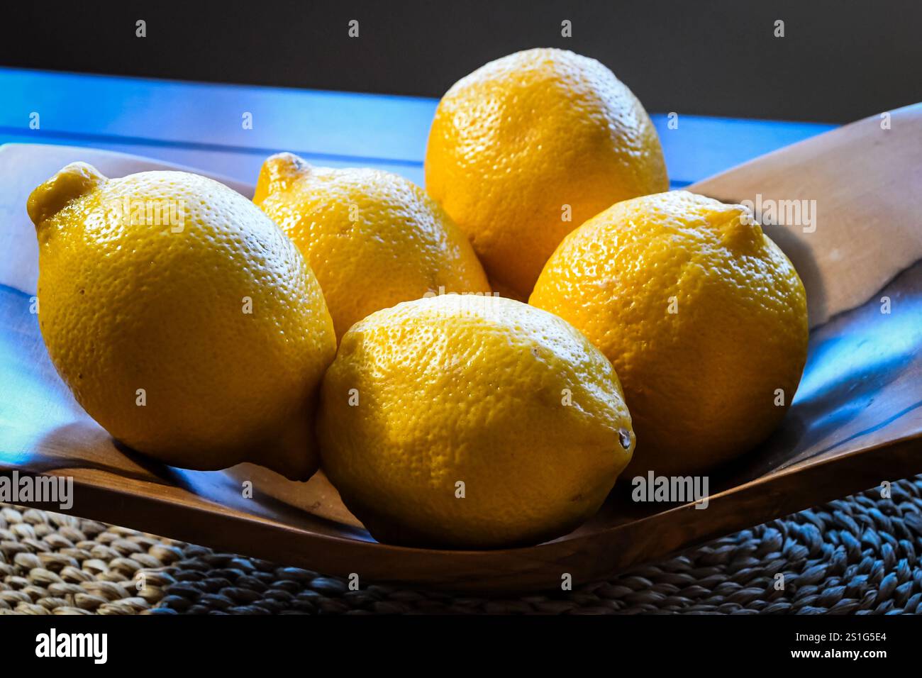 Esposizione di limoni gialli in ciotola di legno Foto Stock