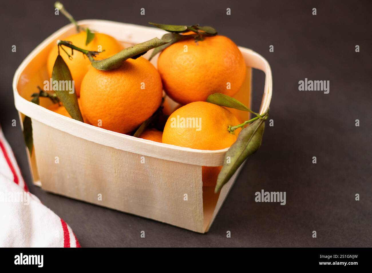 Primo piano di frutta mandarina in una scatola di legno su sfondo grigio Foto Stock