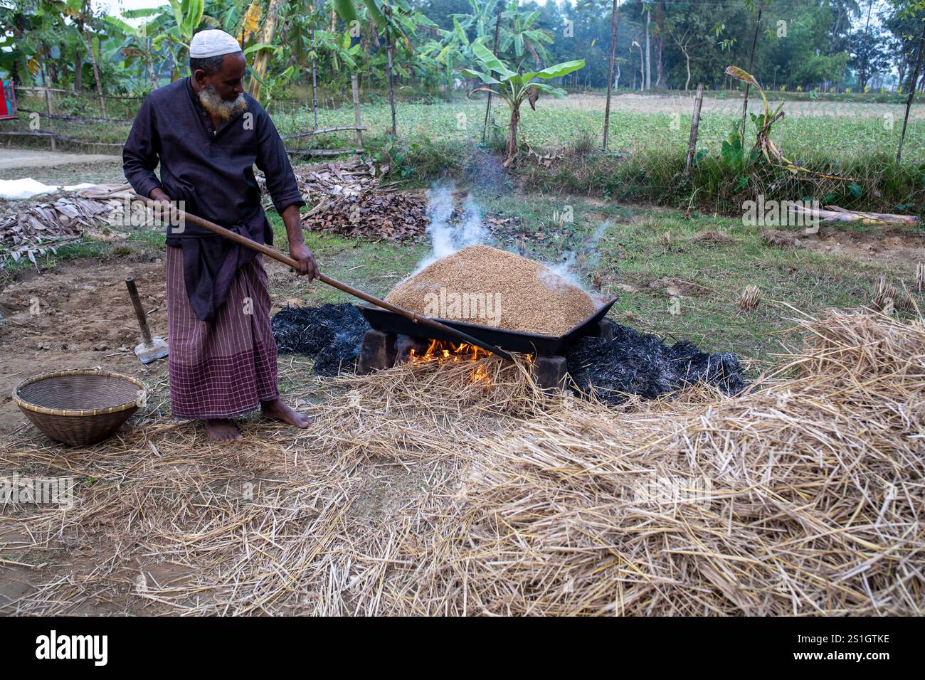 Un agricoltore fa bollire il risone nella regione Haor di Mohonganj, distretto di Netrokona, Bangladesh, durante la stagione del raccolto. Foto Stock