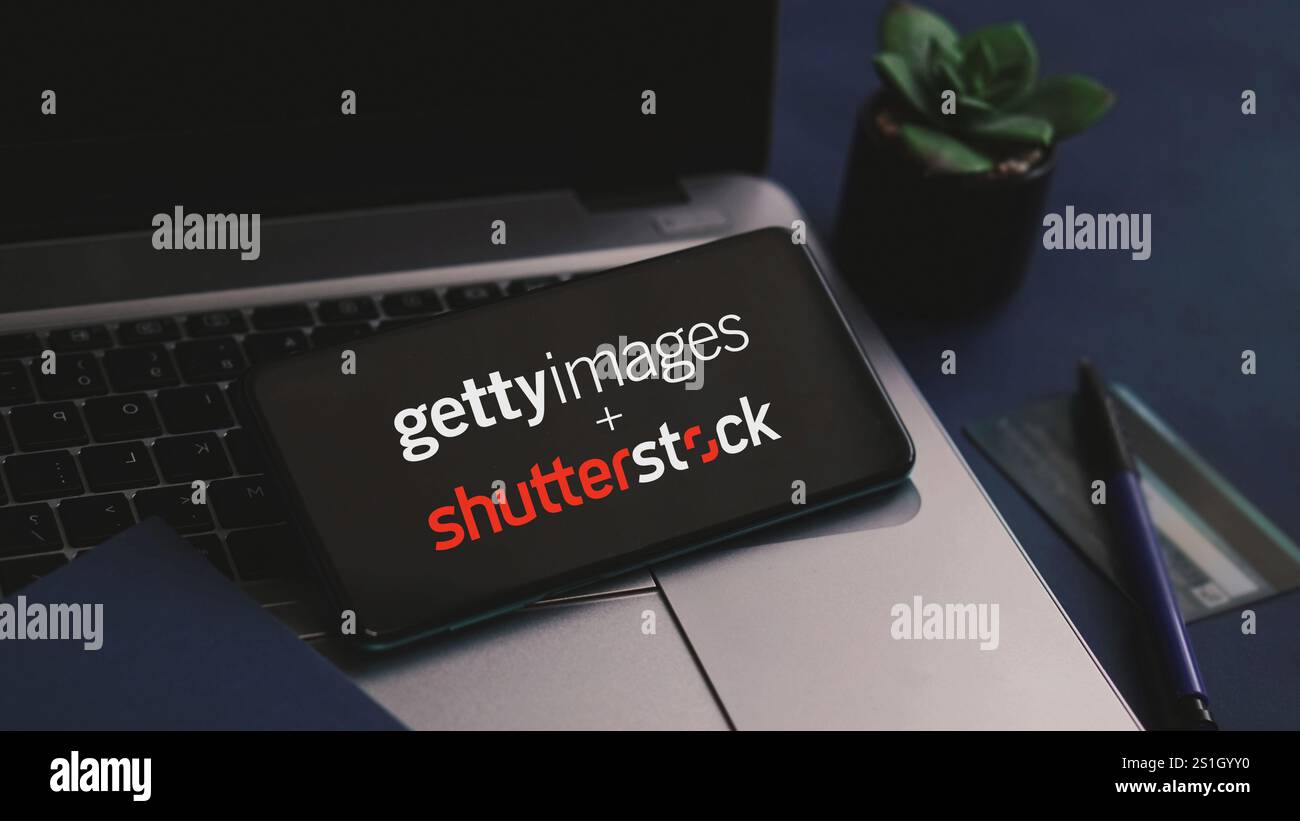 Dobrich, Bulgaria - 4 gennaio 2025: Telefono cellulare su un portatile che mostra la fusione di Getty Images con Shutterstock. Il concetto di fusione di microstock. Foto Stock