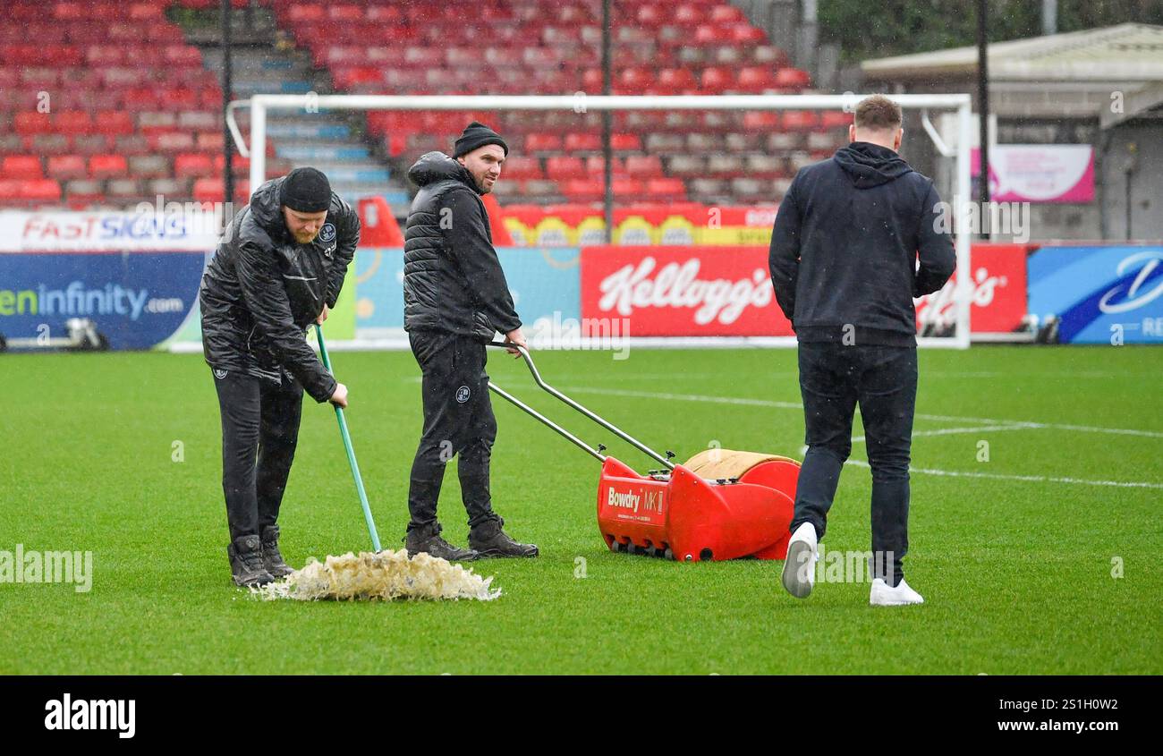 Lo staff di Crawley Town cerca di ripulire l'acqua di superficie sul campo ma la partita è stata successivamente interrotta nella partita Sky Bet EFL League One tra Crawley Town e Charlton Athletic al Broadfield Stadium di Crawley, Regno Unito - 1 gennaio 2025 Foto Stock