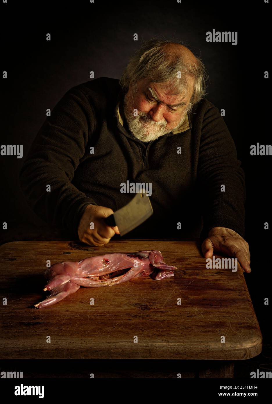 Un uomo che taglia carne di coniglio Foto Stock