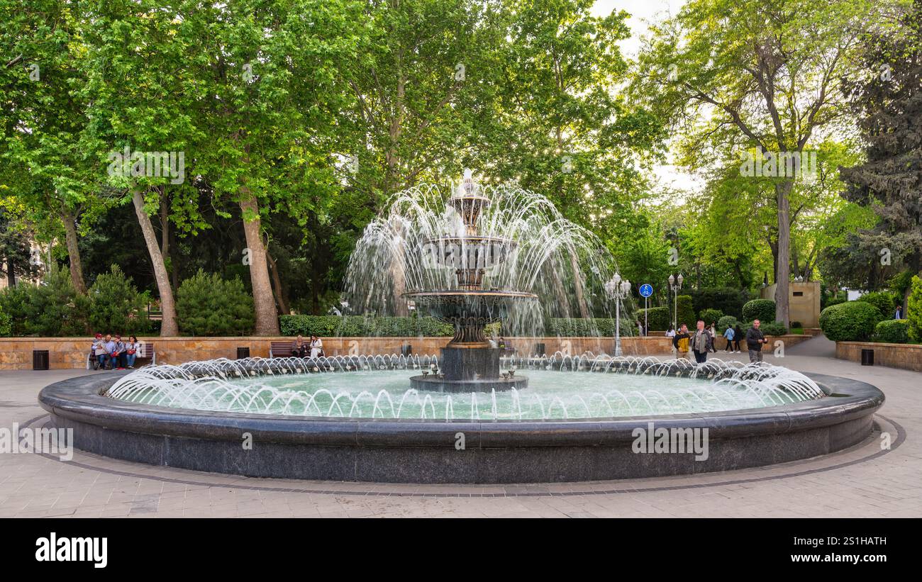 Baku, Azerbaigian - 4 maggio 2024: Fontana Azneft presenta una splendida fontana che danza con l'acqua mentre i visitatori si godono i lussureggianti dintorni accanto alle storiche mura della città vecchia, Icherisheher Foto Stock