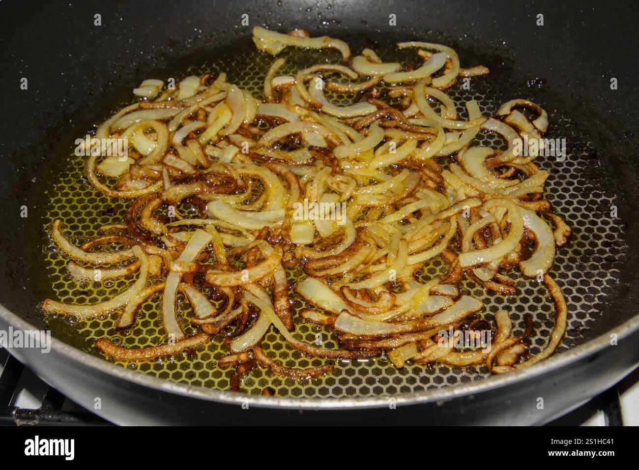 Fette di cipolla caramellate dorate saltate in padella a fuoco medio, brillando con olio d'oliva. Perfetto per esaltare i sapori dei piatti. Il Foto Stock