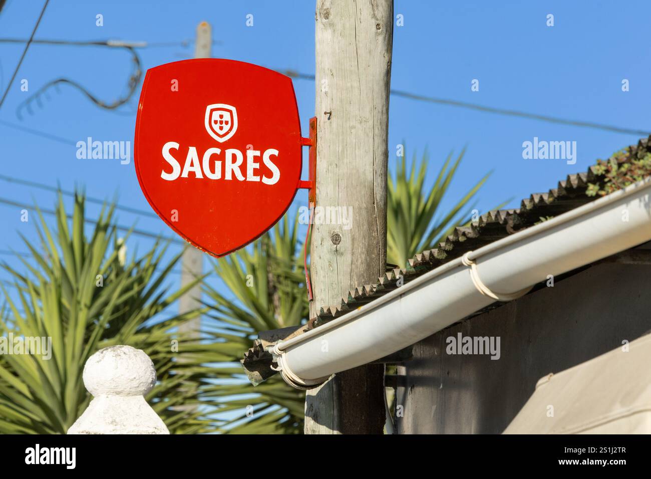 Sesimbra, Portogallo. 7 agosto 2024, cartello con il logo della birra Sagres montato contro un ceppo d'albero. Sagres è una birra portoghese fondata nel 1940. Ora di proprietà di . Foto Stock