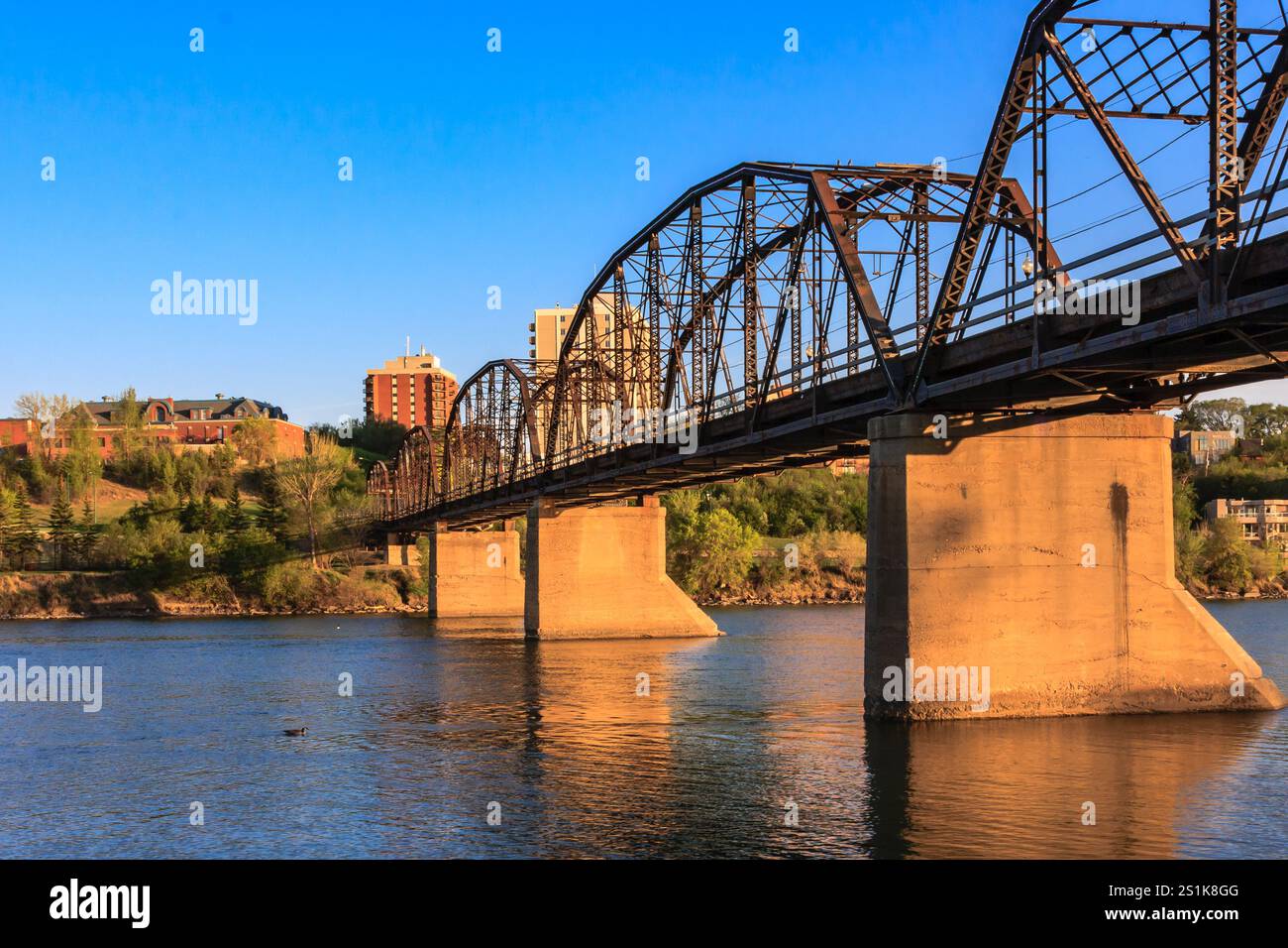 Un ponte attraversa un fiume con una città sullo sfondo. Il ponte è vecchio e ha un aspetto rustico Foto Stock