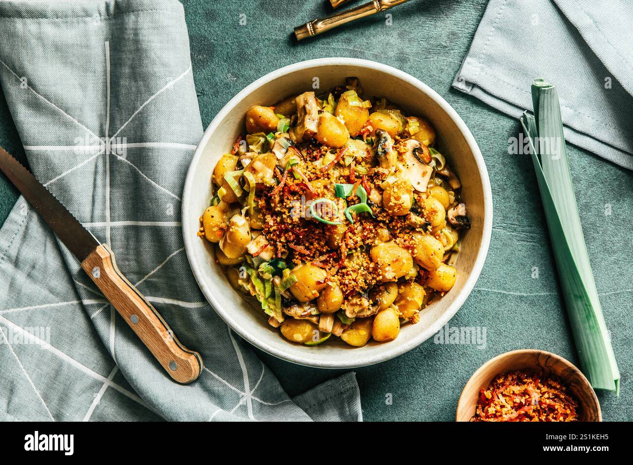 Gnocchi in salsa cremosa di funghi con cipolle primaverili e una croccante copertura di pangrattato, sfondo verde, vista dall'alto Foto Stock