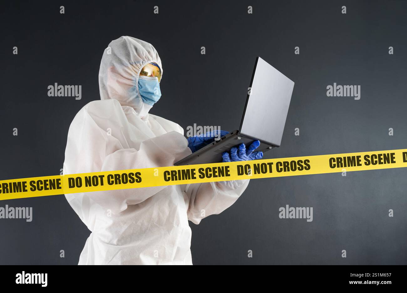 L'analisi legale con laptop in abbigliamento protettivo funziona sulla scena del crimine. Il concetto di risolvere un crimine. Vero crimine. Foto Stock