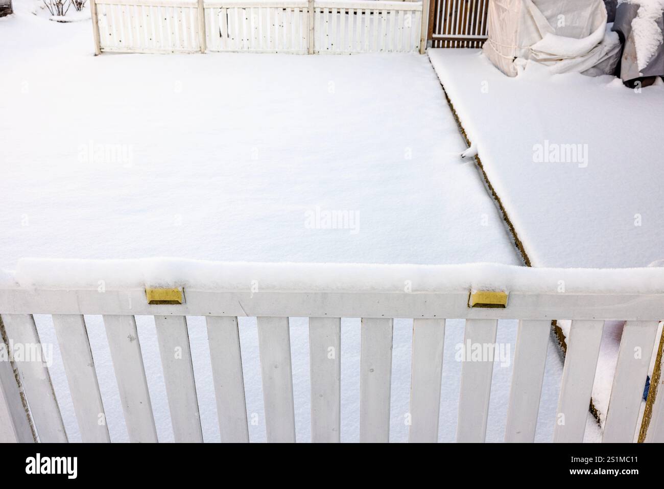 Recinzione in legno bianco ricoperta di neve con neve fresca che crea una serena atmosfera invernale. Foto Stock