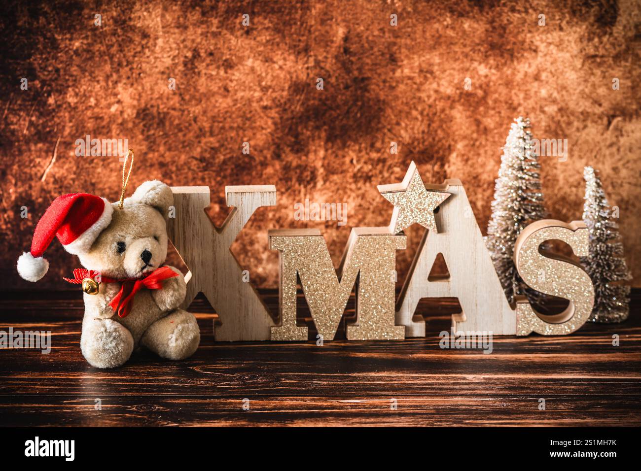 Piccolo orsacchiotto con cappello di babbo natale e lettere in legno, decorazioni natalizie su sfondo in legno, spazio per copie Foto Stock