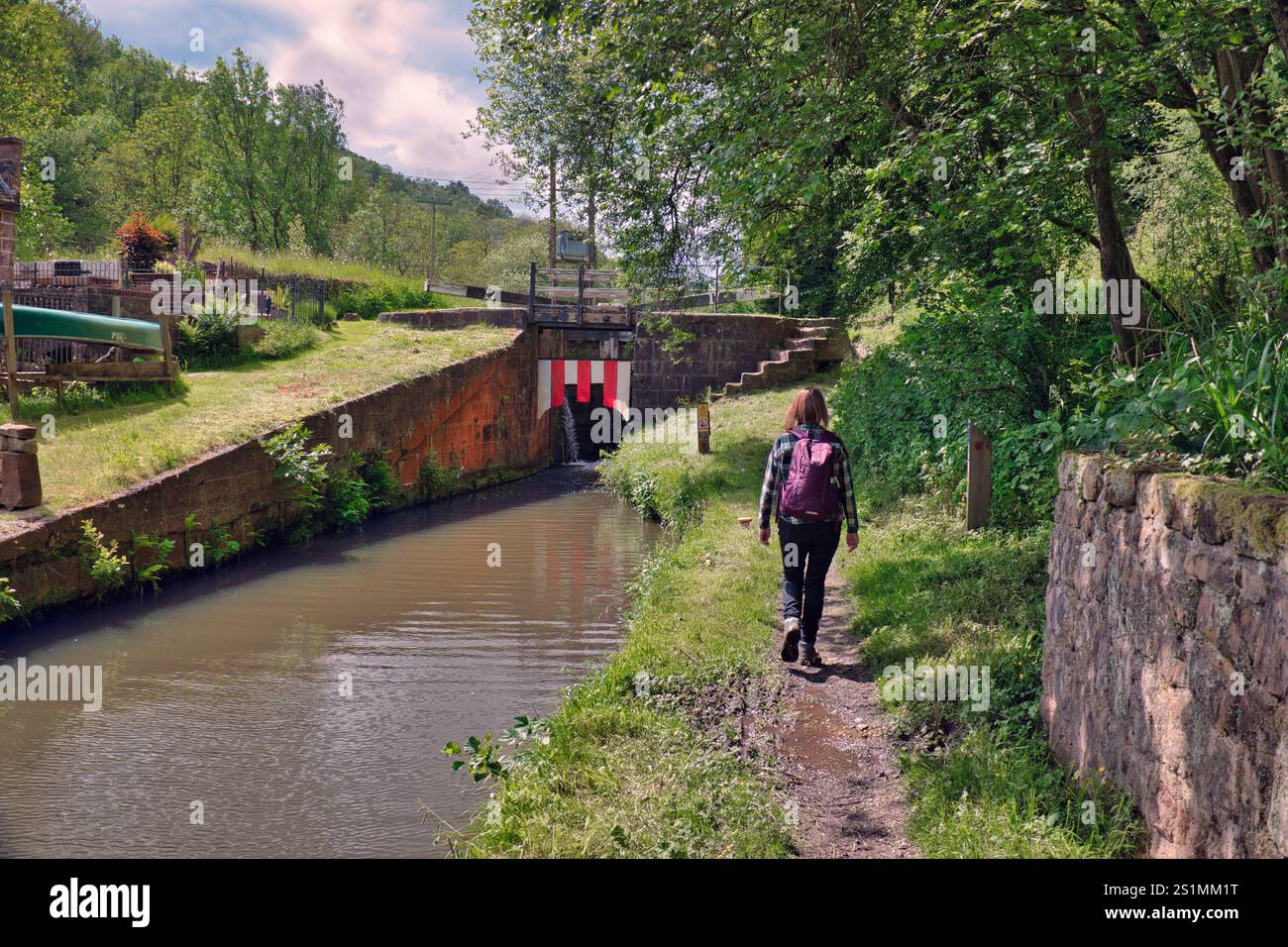 Una donna che cammina lungo il sentiero della Lock 17 del canale di Caldon, noto anche come Flint Mill Lock o Wetley Lock vicino a Consall, Wetley Rocks, Staffordshire, Regno Unito Foto Stock