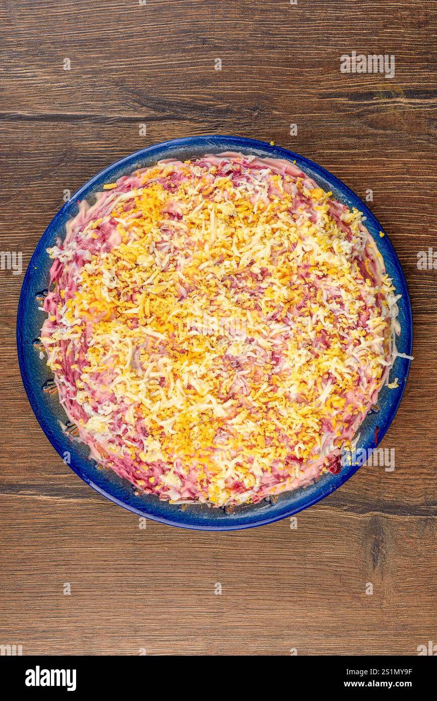 Vista dall'alto di un piatto blu pieno di aringhe sotto un'insalata di pelliccia. Cucina casalinga. Foto Stock