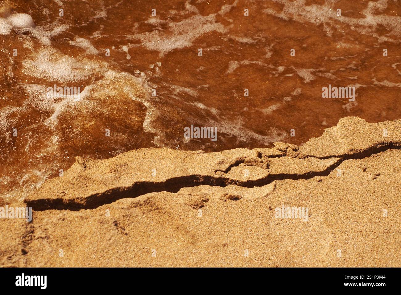 Erosione della sabbia ai margini di una spiaggia sabbiosa dove un fiume scorre nel mare mostrando erosione in azione con l'acqua che scorre veloce. Isola di Lewis, Regno Unito Foto Stock