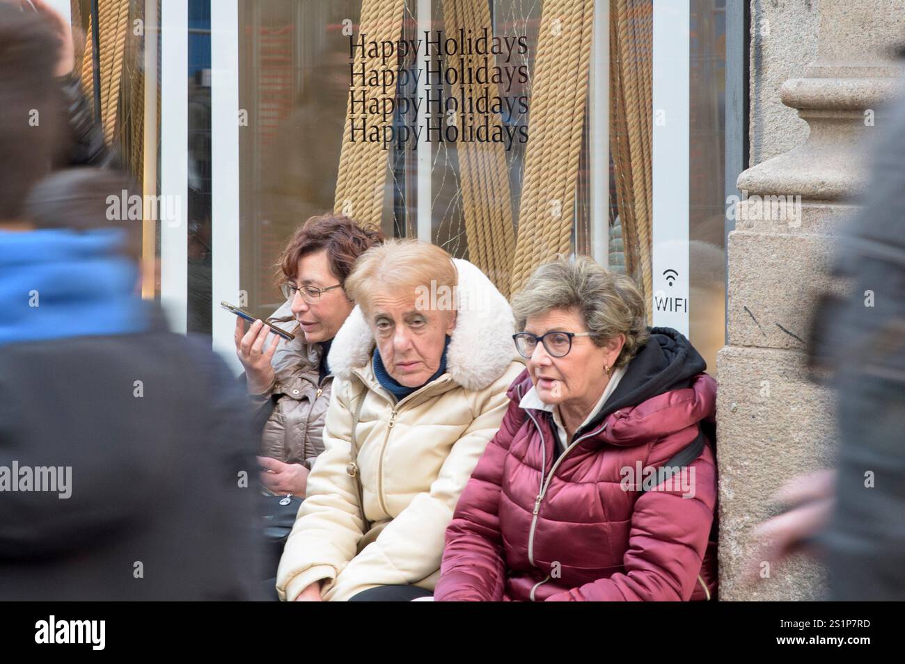 Roma, Italia. 4 gennaio 2025. Tre donne sedute davanti a una vetrina con lo slogan "buone feste" ripetuto sopra la testa il giorno in cui sono iniziati i saldi invernali a Roma. La stagione invernale è ufficialmente iniziata a Roma e nel Lazio. Secondo i risultati di un sondaggio condotto da Confcommercio Roma in collaborazione con Format Research, sulle intenzioni di acquisto dei romani per i saldi invernali, il 70% dei consumatori intervistati prevede di usufruire degli sconti, con un budget medio di 178 euro. In Italia, anche nel 2025, le date di inizio delle vendite variano da regione a regione, ma la maggior parte ha annunci pubblicitari Foto Stock
