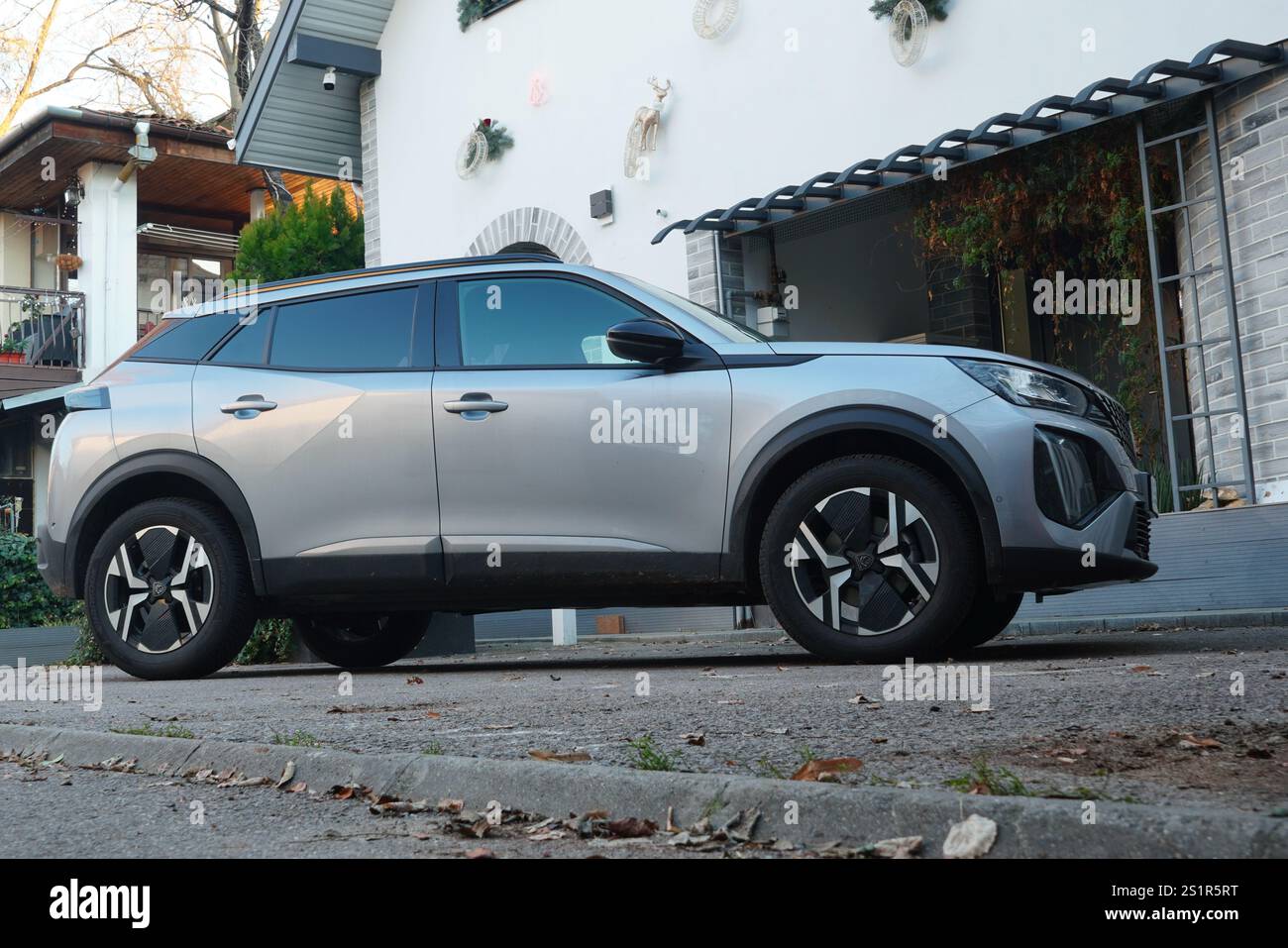 Bucarest, Romania – 1 gennaio 2025: Vista laterale della Peugeot 2008 ibrida argentata parcheggiata di fronte alla casa Foto Stock