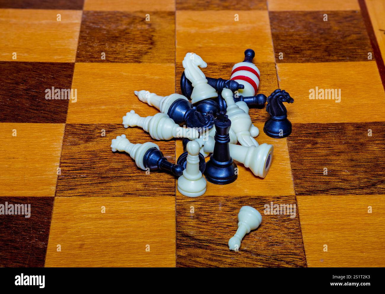 Una disposizione caotica di scacchi bianchi e blu è sparsa su una scacchiera di legno, indicando la conclusione di una partita competitiva. La sc Foto Stock