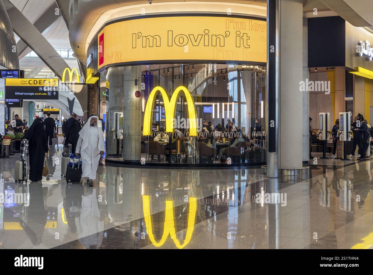 Aeroporto di Abu Dhabi, aeroporto internazionale di Zayed con passeggeri. Ristorante McDonalds. Il nuovo Terminal A ha una capacità di 45 milioni di passeggeri per anno Foto Stock