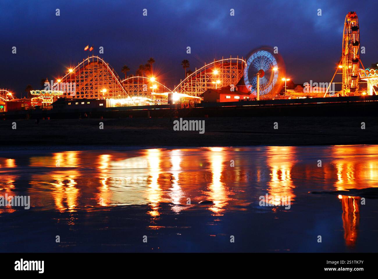 Le giostre del parco divertimenti sul lungomare di Santa Cruz California sono illuminate e riflesse nel vicino ruscello Foto Stock