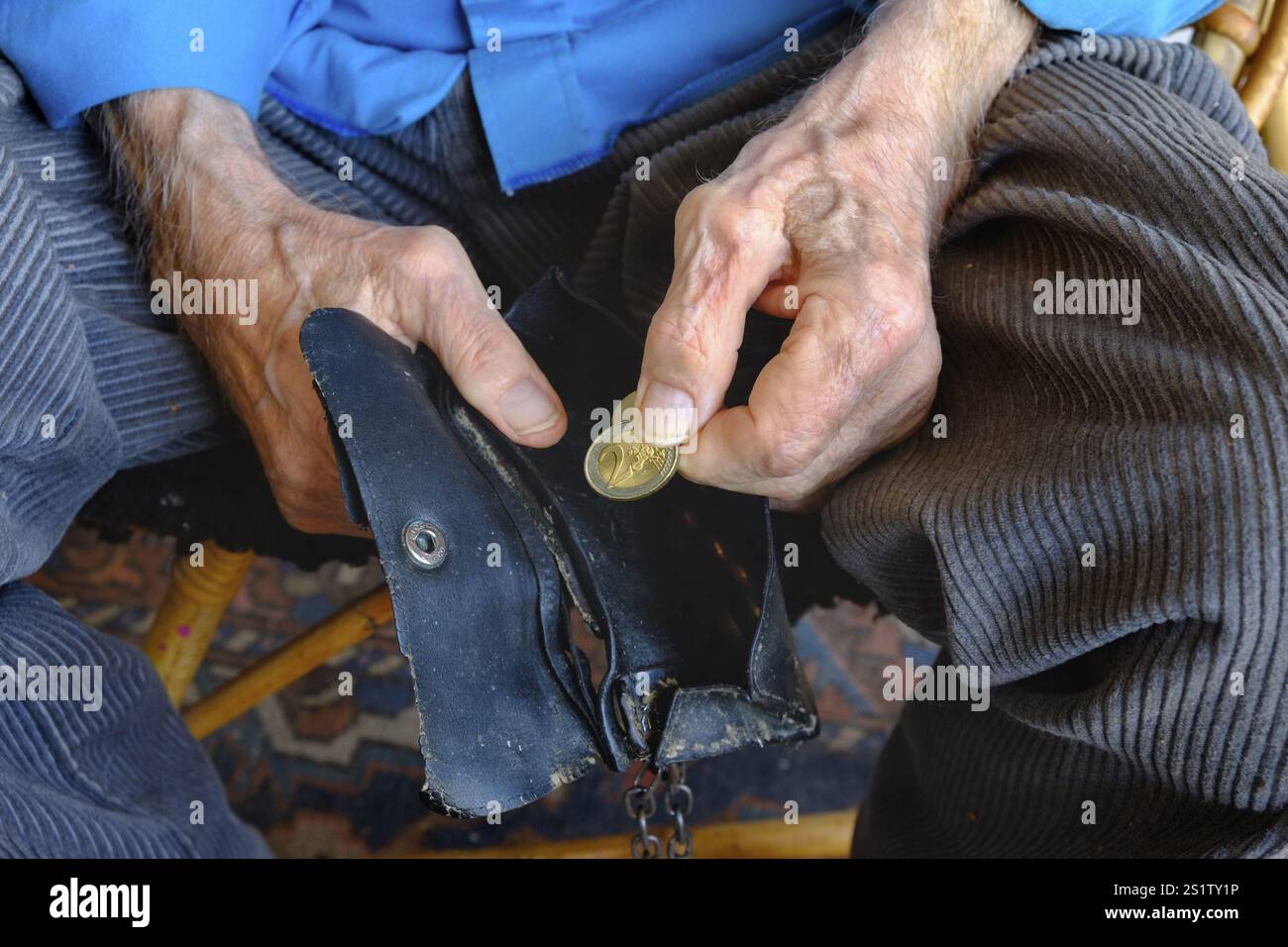 Un vecchio prende una moneta da due euro dal suo portafoglio. Primo piano, formato orizzontale. Un vecchio prende una moneta da due euro dalla sua borsetta usurata. Chiudere u Foto Stock