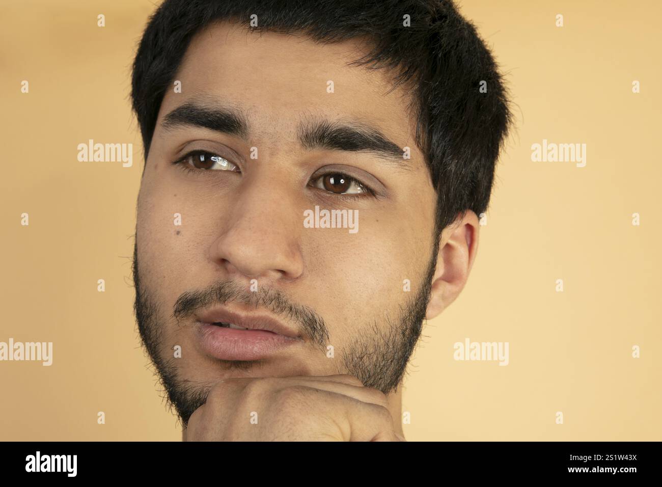 Ritratto di un giovane uomo attraente in uno studio con sfondo beige Foto Stock