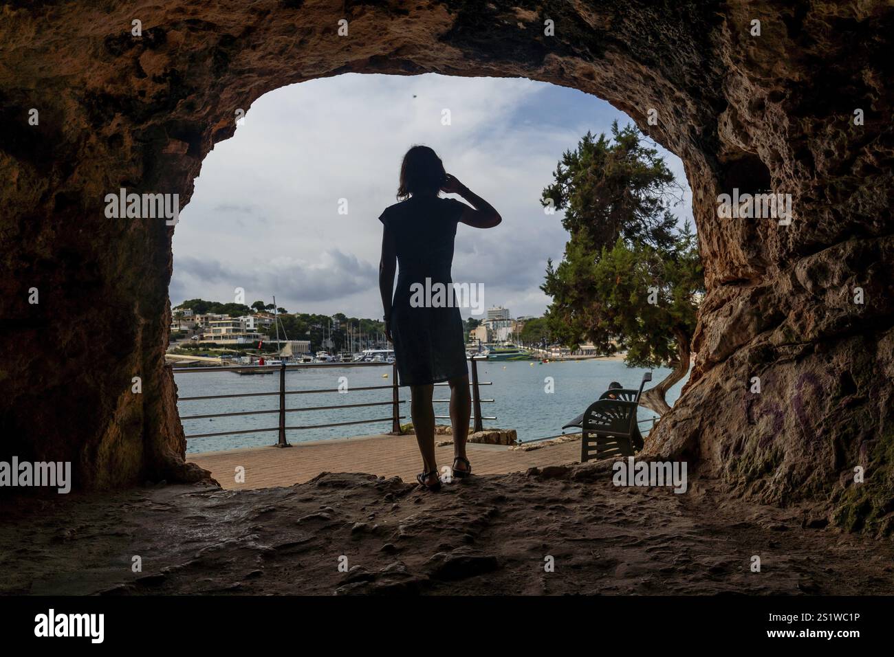 Il turista protegge gli occhi dal sole mentre si gode la vista del porto di puerto cristo, maiorca Foto Stock