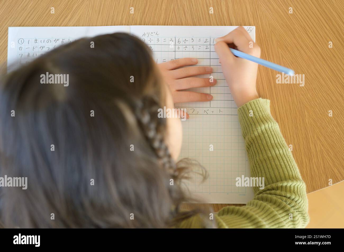 Vista dall'alto delle mani di una ragazza che risolvono problemi di matematica Foto Stock