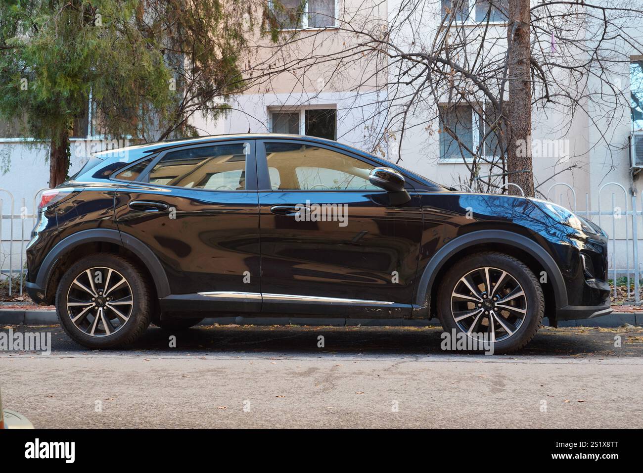 Bucarest, Romania – 4 gennaio 2025: Vista laterale dell'auto nera ibrida Ford Puma parcheggiata sulla strada di fronte al blocco di appartamenti Foto Stock