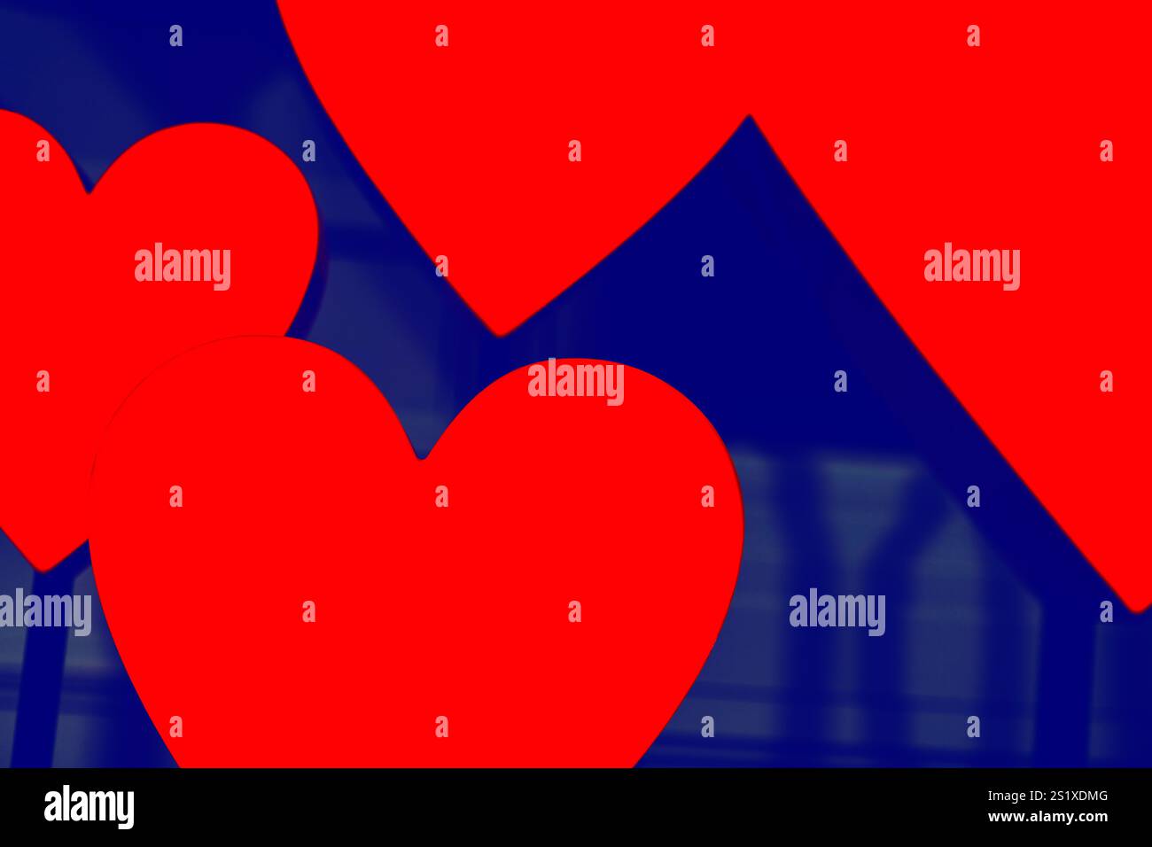 Il cuore rosso si forma su sfondo blu. I cuori si sovrappongono leggermente, con un cuore significativamente più grande degli altri. Contrasto tra Foto Stock