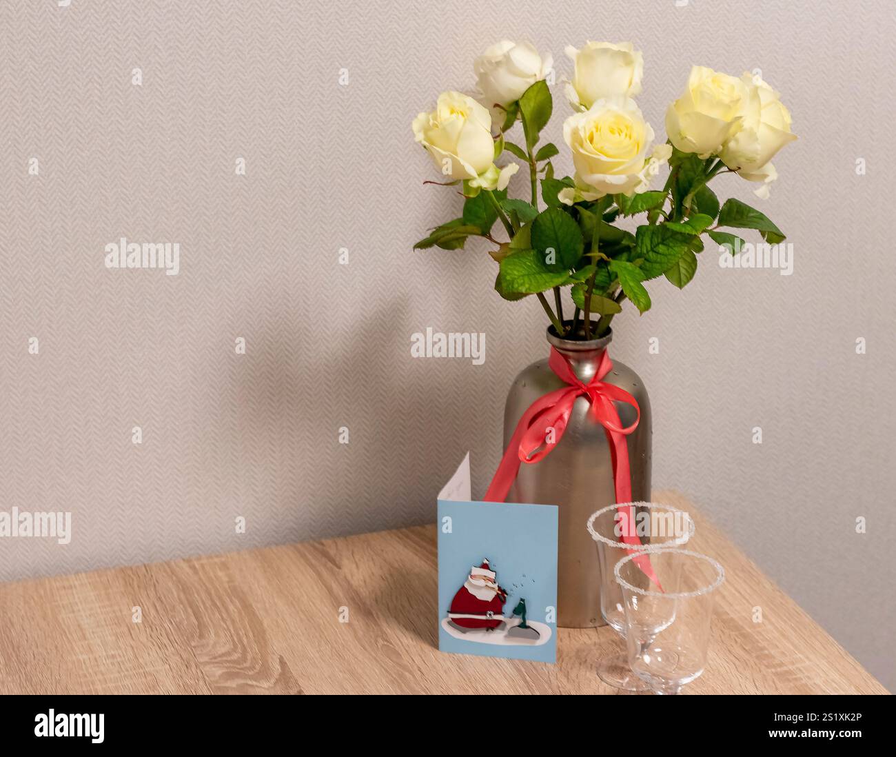 Shot delle rose bianche in un elegante vaso in metallo. Biglietto di auguri di Natale accanto ad esso. Foto Stock