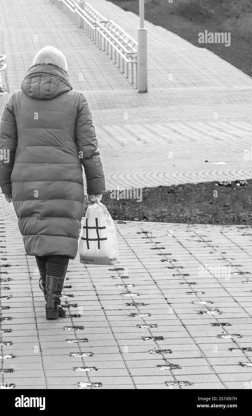 Donna con un sacchetto di plastica e un'illustrazione con hash tag che cammina all'aperto Foto Stock