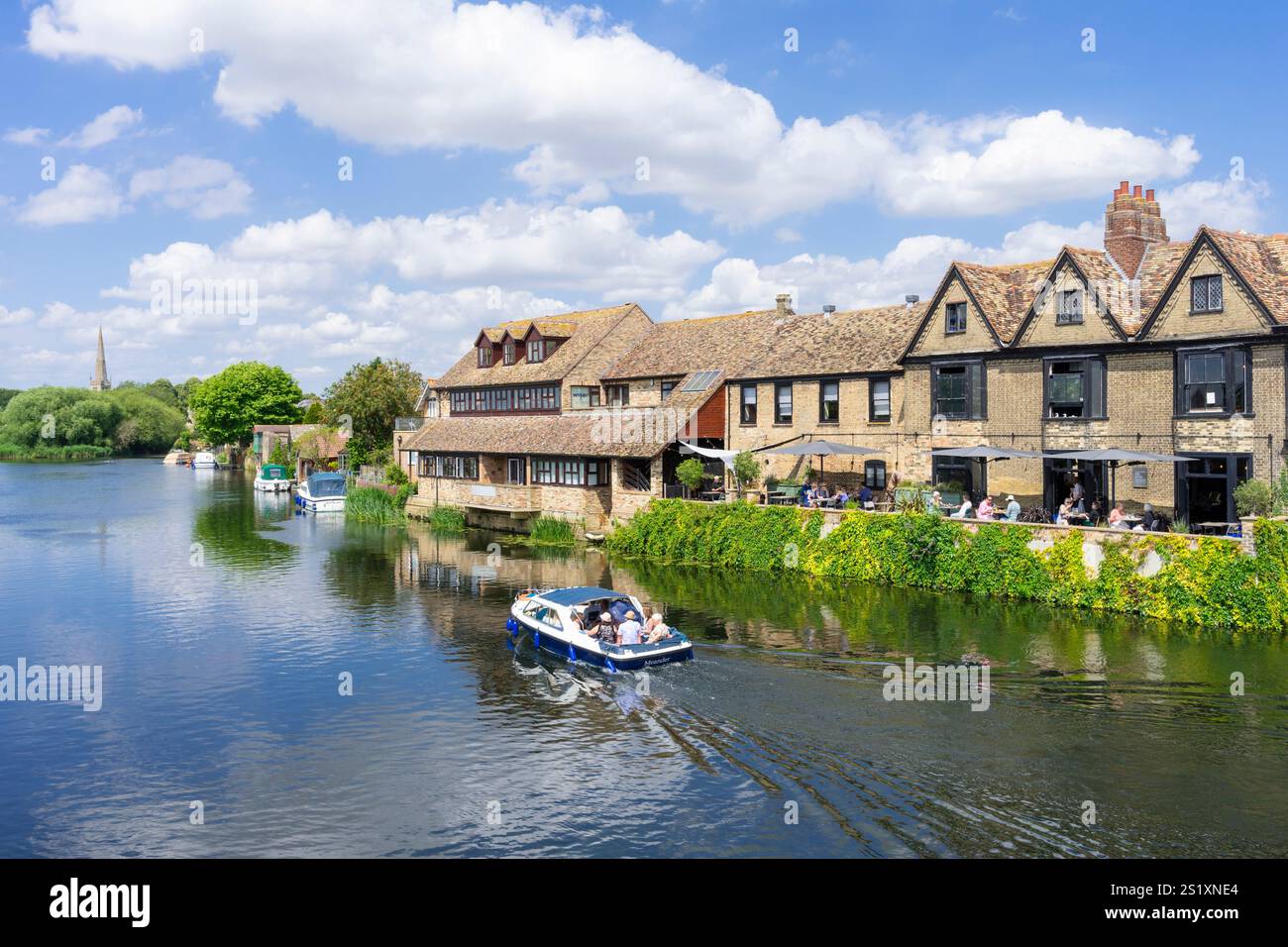 Il motoscafo St Ives passa davanti al caffè River Terrace vicino al fiume Great Ouse a St Ives Cambridgeshire Inghilterra Regno Unito Europa Foto Stock