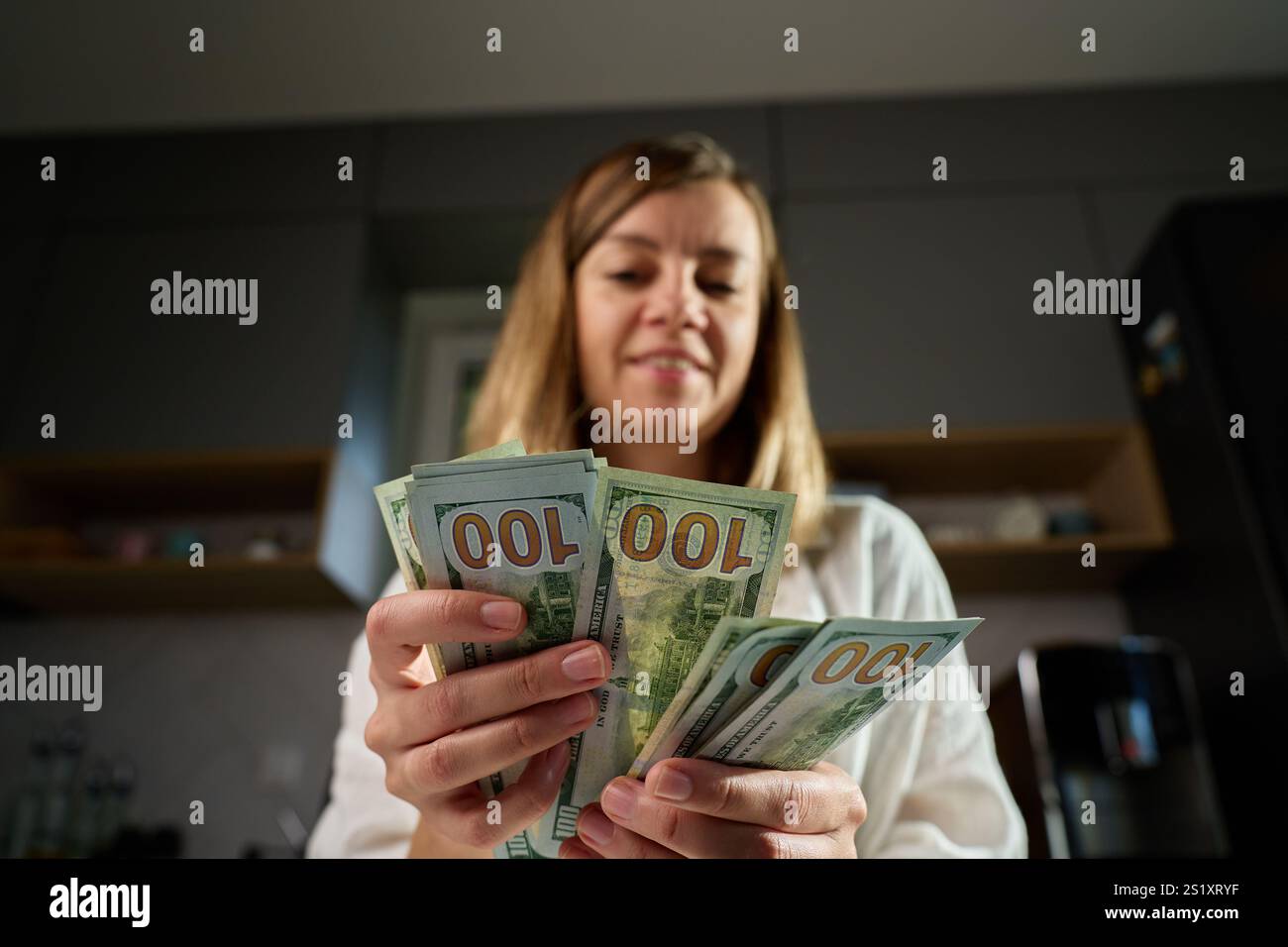 Donna che conta un mucchio di banconote da un dollaro a casa. Donna che tiene in mano dollari americani in contanti. Concetto di gestione del contante, ricchezza o transazioni finanziarie Foto Stock
